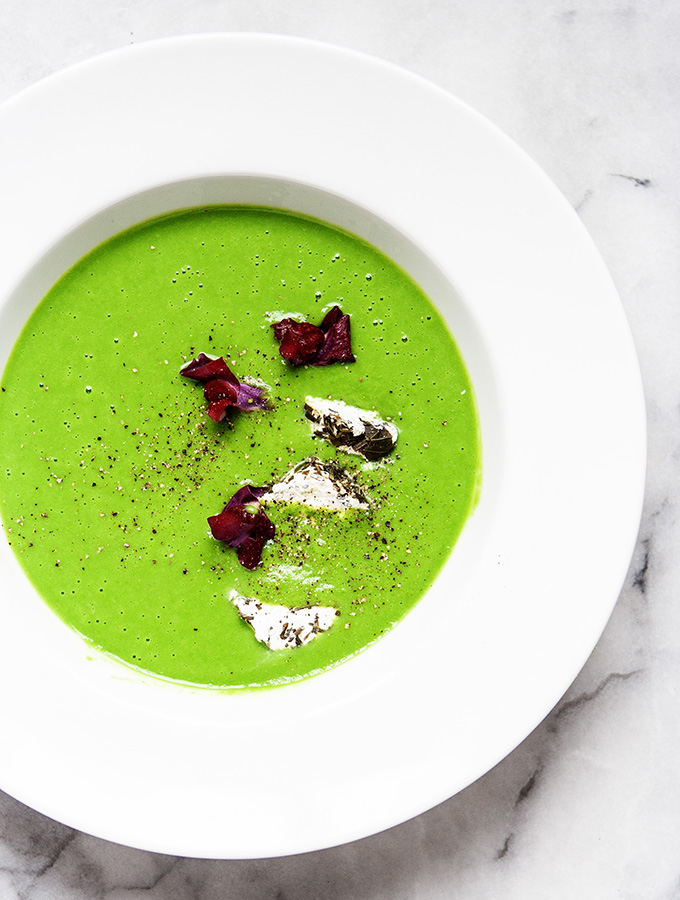The verdant green of Spring is all here in this Little Jewel from the Kitchen-Chilled Pea Velouté with Goat Cheese & Edible Flowers No. 639 in the Membership Collection. ENGLISH GREEN PEAS I can't think of any vegetable that announces Spring like fresh green peas. This is a simple soup, just place frozen peas in the blender with boiling water and voilà, the chilled soup is ready. VELOUTE´ These French soups are typically created with stock and a roux, but this Little Jewel comes together smooth and creamy with just a flick of the blender. The frozen peas are whizzed with boiling water in the blender, then set aside to fully chill in the refrigerator. Perfect. GOAT CHEESE & EDIBLE FLOWERS The crowning jewels to this soup are slices of herbed Goat cheese and a sprinkling of edible flowers. The goat cheese logs are fairly common, if not just roll a plain log in some of your favorite dried herbs. I usually try to grow edible flowers in pots, but the gloomy beach weather has postponed Spring planting. I found these edible flowers at, where else, Trader Joes. Chilled Pea Velouté with Goat Cheese & Edible Flowers | Bijouxs Little Jewels 